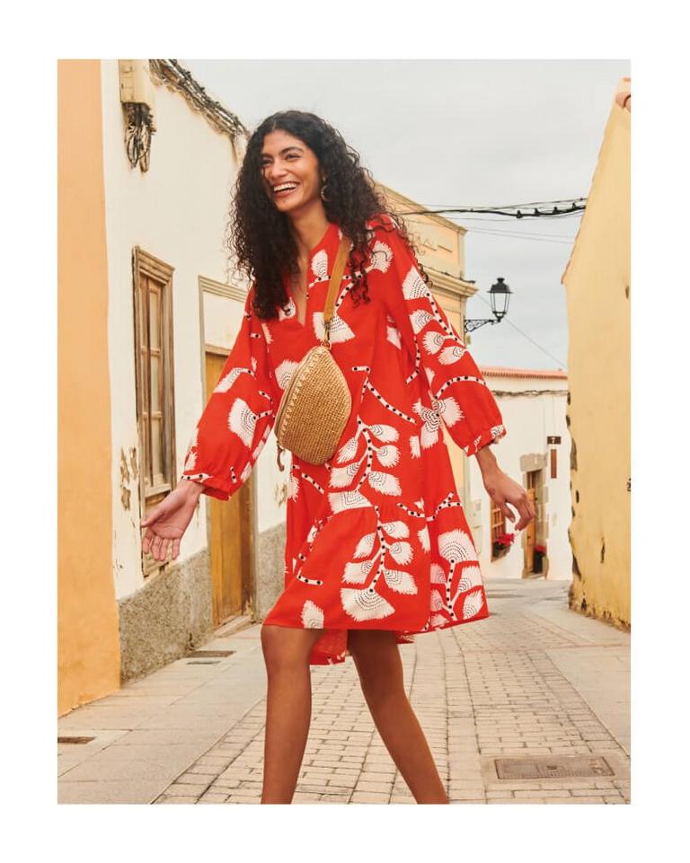 Woman in red printed linen dress walking across street